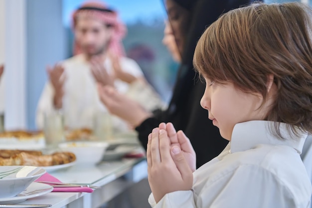 Muslim family making iftar dua to break fasting during Ramadan. Arabian people keeping hands in gesture for praying and thanking to Allah before traditional dinner