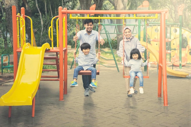 Muslim family playing with swings