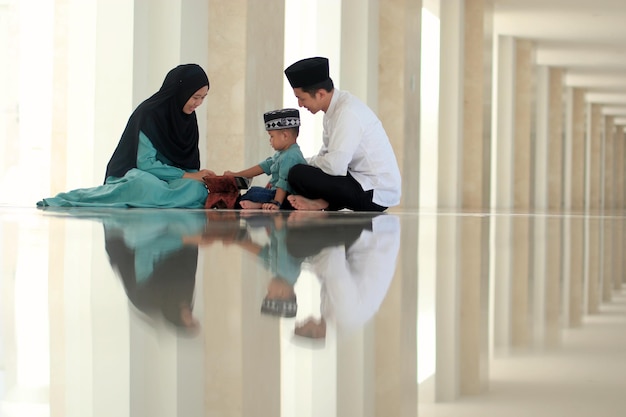 Photo a muslim family sits on the floor in a mosque.