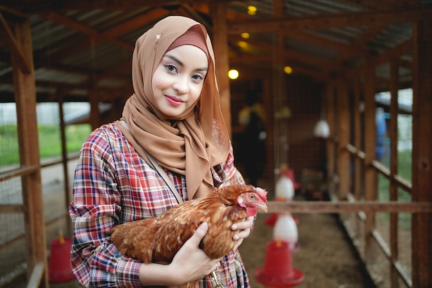 Muslim farmer in the chicken farm holding a chicken