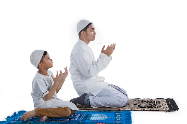 Muslim father and son praying together isolated over white background