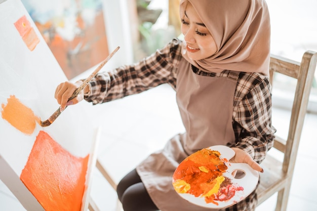 Muslim female artist painting on canvas at home studio