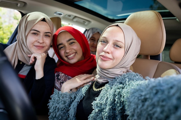 Muslim female friends enjoying road trip traveling at vacation in the car. High quality photo