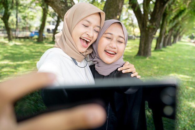 muslim friend taking selfie or video calling outdoor using her smart phone during sport