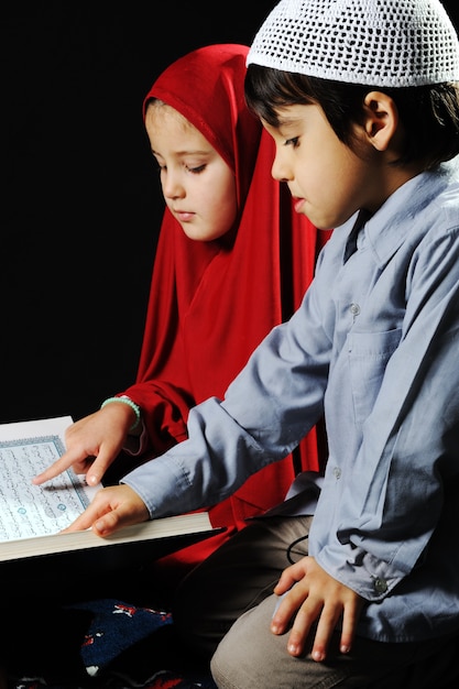 Фото Мусульманская девушка и мальчик на черном фоне чтение коран