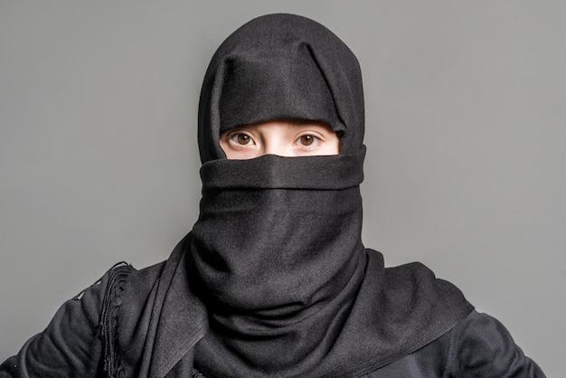 muslim girl in black hijab on gray background
