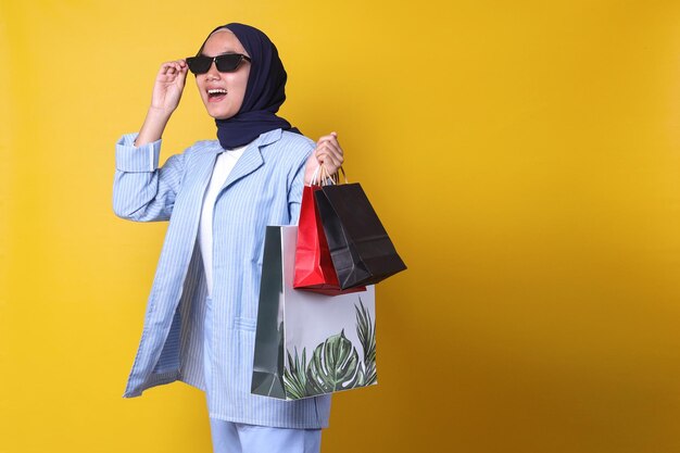 muslim girl in casual style is feeling happy to shopping, carrying a lot of shopping bags