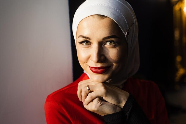 Muslim girl is praying at home. Close-up portrait of muslim model weared in traditional islamic scarf. Islam religion.