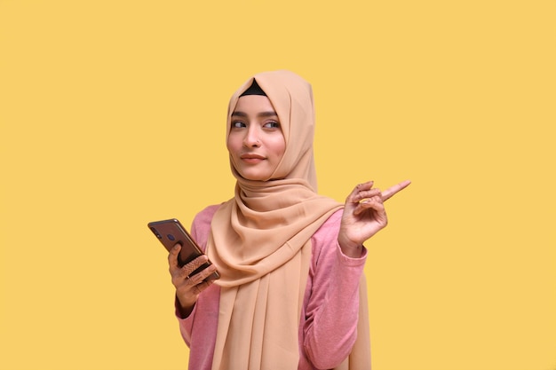 muslim girl wearing hijab holding phone and looking away indian pakistani model