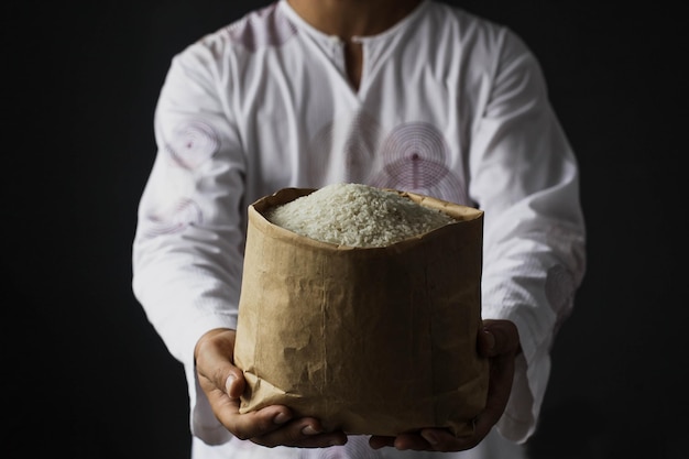 Photo muslim hand holding alms bag of rice isolated on black background