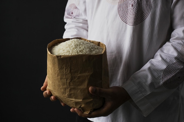 Muslim hand holding alms bag of rice isolated on black background