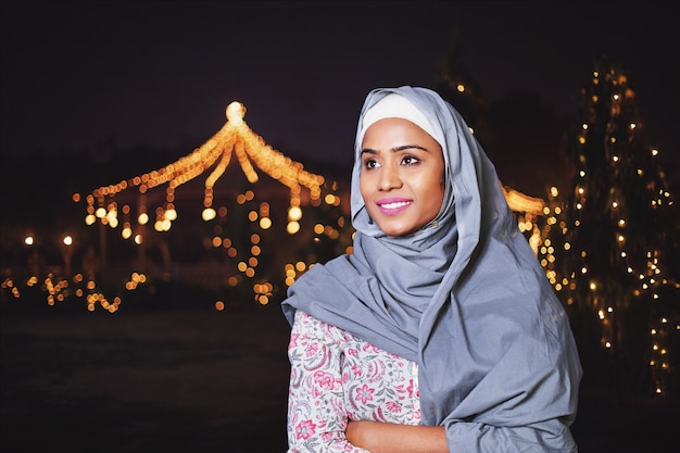 Muslim Indian woman near decorated garden at night in Ramadan