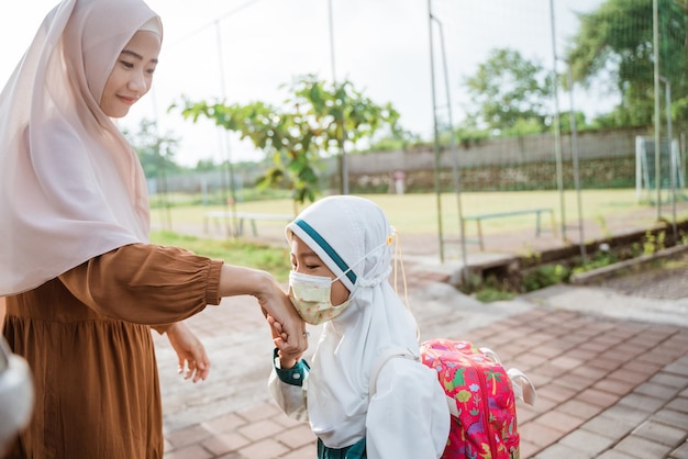 Photo muslim kid kiss her mother hand before entering school