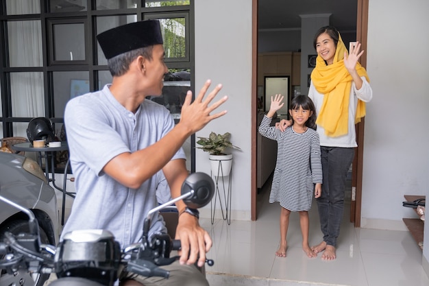 Muslim man going by motorcycle scooter leaving his family behind at home asian family travelling