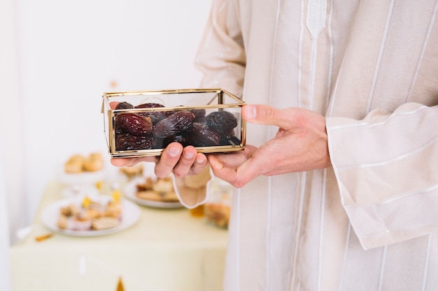 Foto uomo musulmano che tiene scatola di date