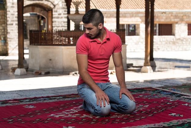 イスラム教徒の男性が屋外のモスクで祈っています