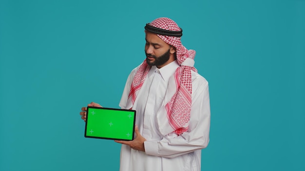 Photo muslim man presents greenscreen tablet