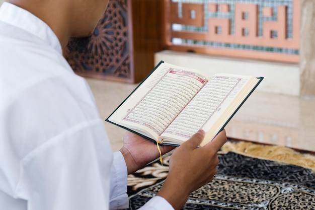 Muslim man reading holy Quran Holy Quran in Hand with arabic text meaning of Al Quran Islamic concept background