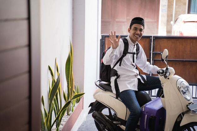 イスラム教徒の男性がスーツケースを運ぶイドゥルフィトリバリクカンポンムディクのオートバイに乗る