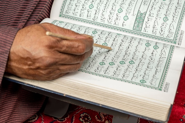 Muslim man sitting and reading the Quran on the prayer rug