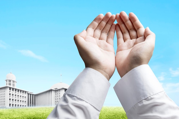 Muslim man standing while raised hands and praying