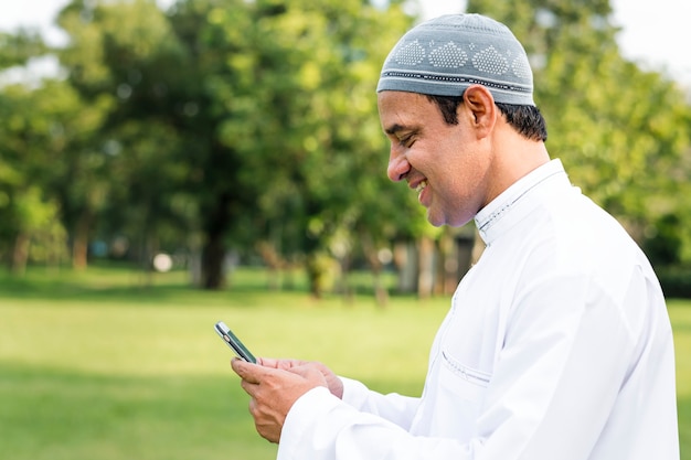 Uomo musulmano che utilizza uno smartphone nel parco