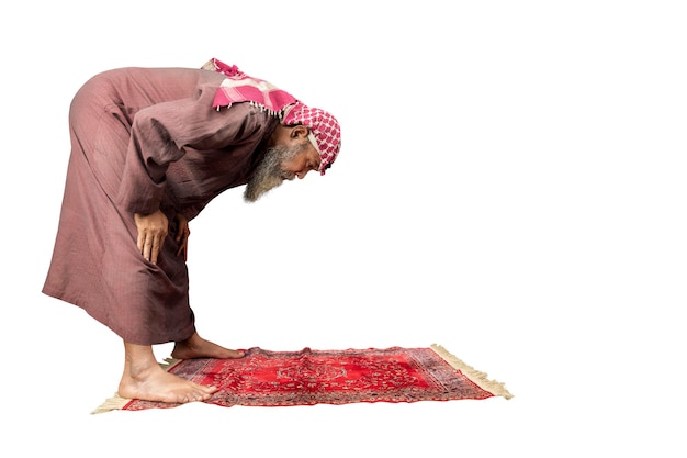 Muslim man with a beard wearing keffiyeh with agal in praying position salat on the prayer rug