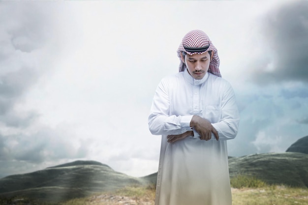 Muslim man with keffiyeh with agal in praying position salat