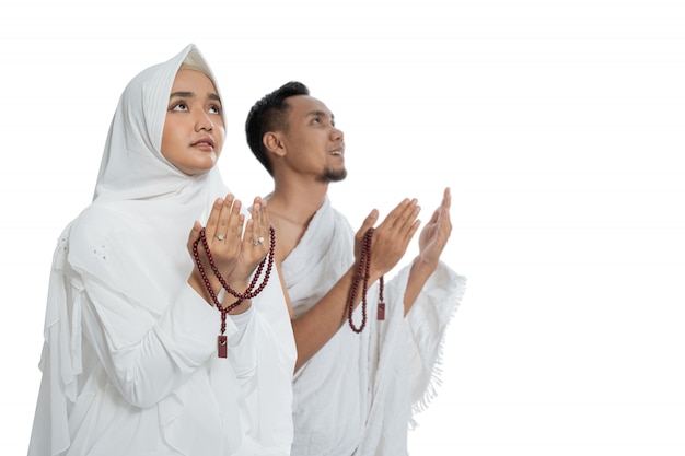 Uomo e donna musulmani che pregano in ihram tradizionale bianco dei vestiti