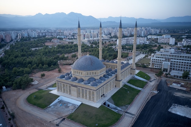 トルコ、アンタルヤのイスラム教モスク。青いモスクミナレットと山々を背景にした街のスカイラインの上面図。