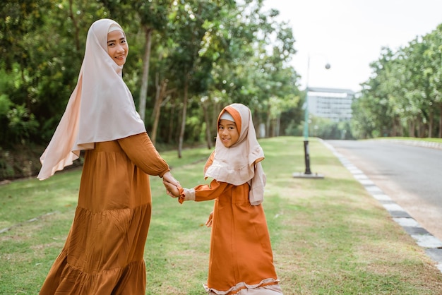 Muslim mother and daughter walking and hold hand together