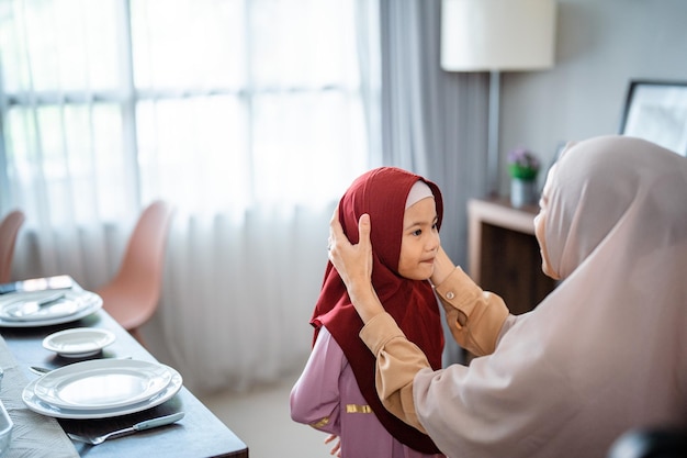 Muslim mother fixing her dauhgter headscarf on ramadan