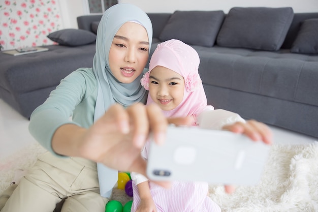 Muslim mother future motherhood in hijab and taking self portrait in living room