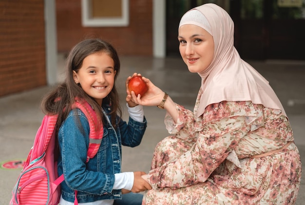 Muslim mother and a happy child girl getting ready for the first school day packing for lunch break.