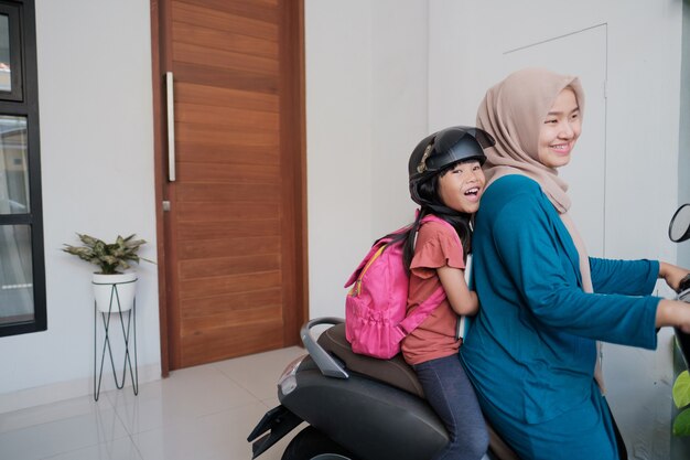 La mamma musulmana porta la figlia a scuola in moto al mattino