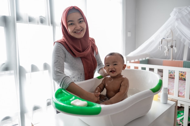 Muslim Mother washing little boy in bathtub