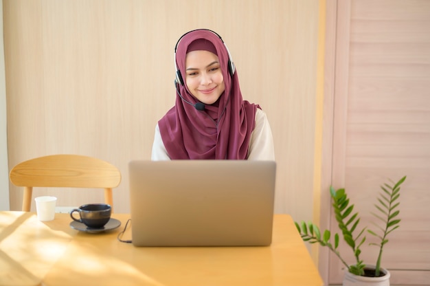 A muslim operator woman in headset using computer answering customer call in office, Customer service concept