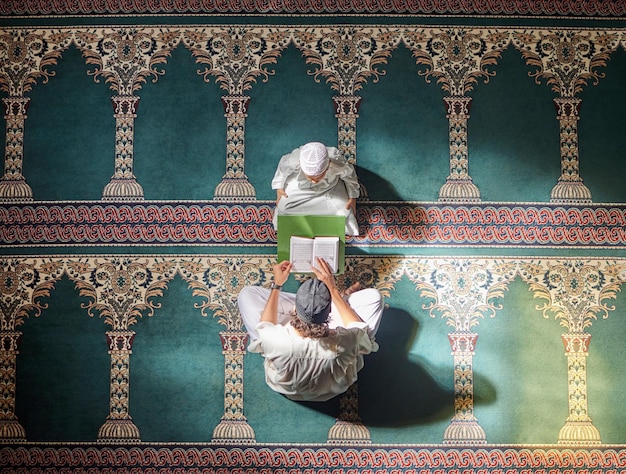 Фото Мусульманин молится ребенку или мужчине в молитве с кораном о мире, внимательности или поддержке аллаха в священной мечети вид сверху исламский ребенок или человек, изучающий или молящийся, чтобы помочь поклоняться богу в рамадан карим