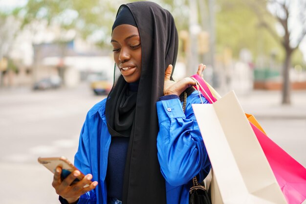 Photo muslim shopper texting on smartphone