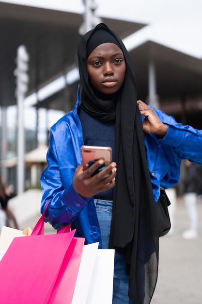 Photo muslim shopper with smartphone walking on street