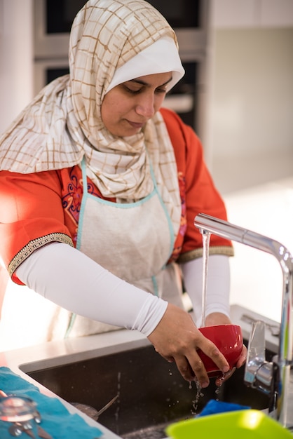 Foto donna tradizionale musulmana che pulisce nella cucina