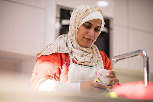 Muslim traditional woman cleaning in kitchen