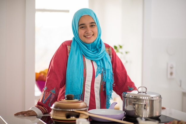 Muslim traditional young girl making food in kitchen