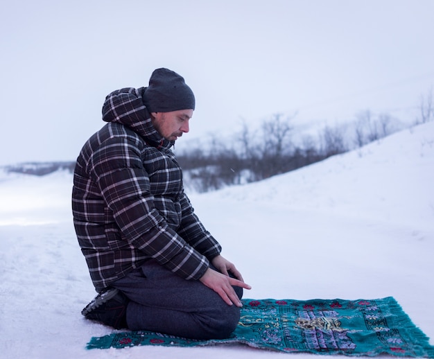 겨울 산에서기도하는 이슬람 여행자