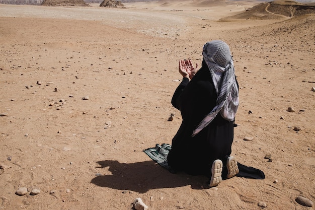 A Muslim with robe clothes praying on the desert