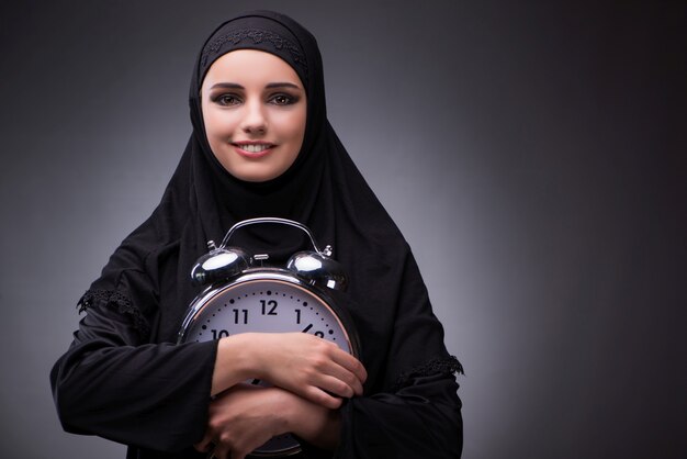 Muslim woman in black dress against dark background