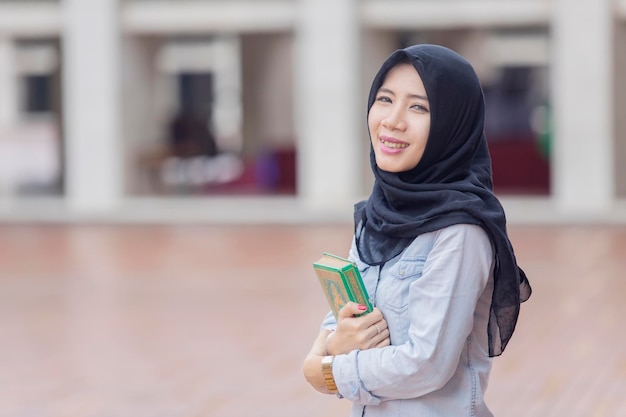 Muslim woman carrying a Quran in the mosque