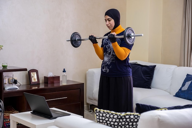 무슬림 여성이 집에서 운동을 하고 있습니다.