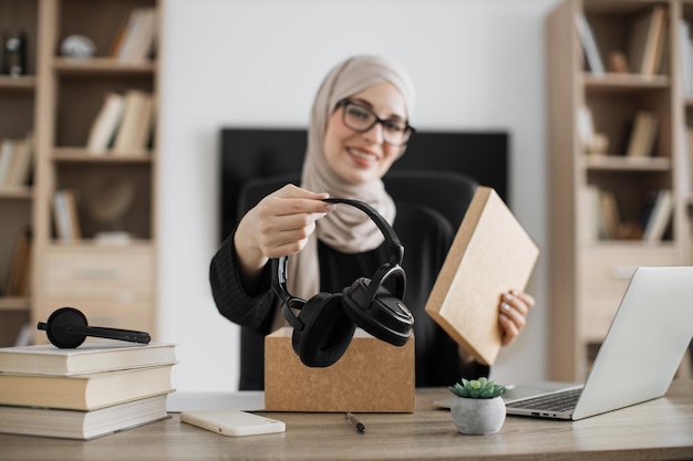 Muslim woman doing live stream while unpacking box with new headphone