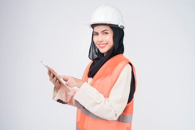 흰색 배경 스튜디오 위에 보호 헬멧을 쓴 이슬람 여성 엔지니어